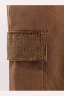 Beige gucci men’s canvas shorts featuring a brown corduroy cargo pocket with textured weave and dark metal snap closure