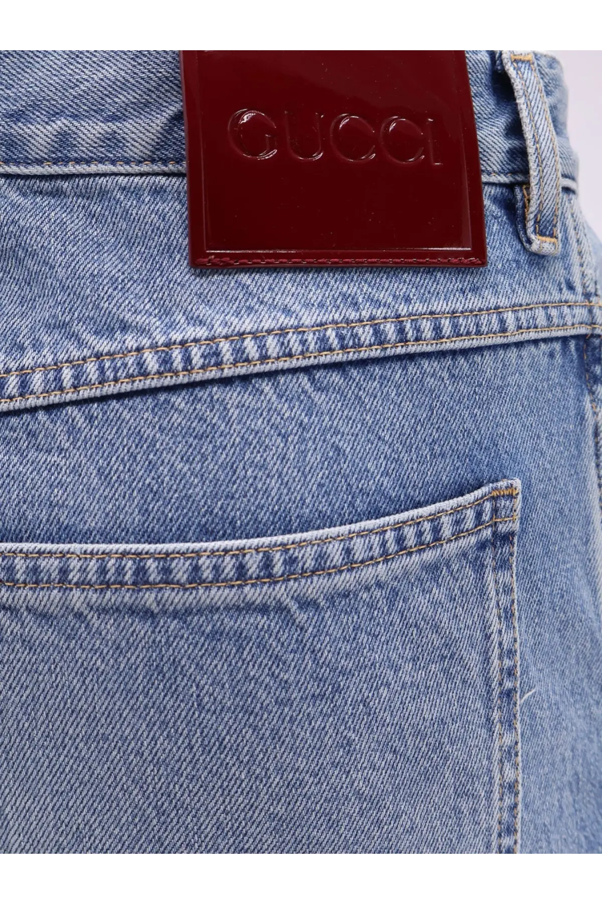 A glossy burgundy leather patch with the embossed gucci logo sewn on the back of light-wash gucci men’s slim fit jeans