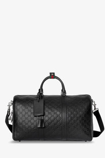 Black Gucci men’s coated canvas GG emblem travel bag with leather duffel design and red green webbing handle accent