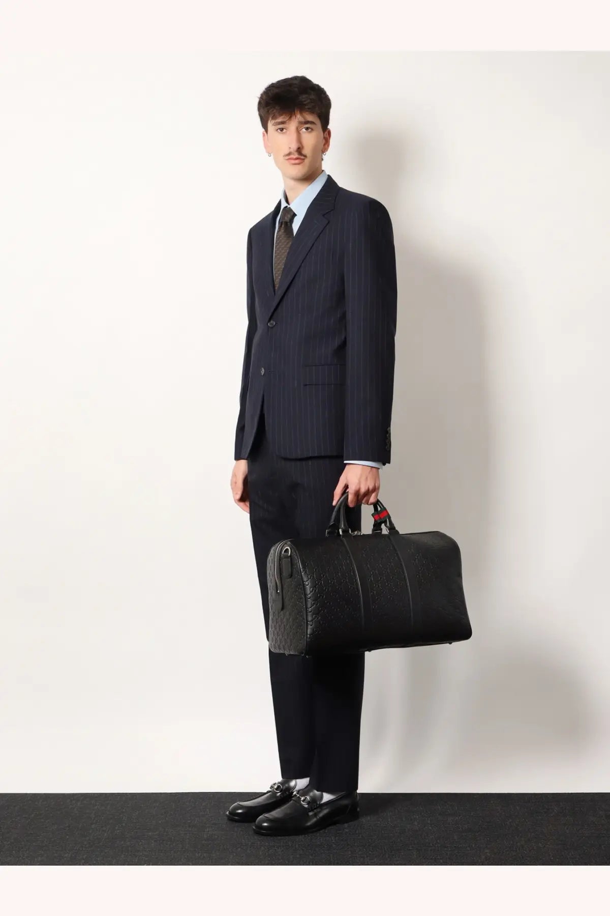 Black textured leather gucci men’s duffel bag with red and black handles for travel use