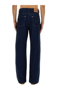 Back side of gucci men’s dark blue denim jeans with rose embroidery on pocket and brown leather waistband patch