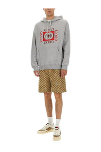 Gray gucci hoodie with bold red and black logo print across the chest paired with beige fabric shorts for men