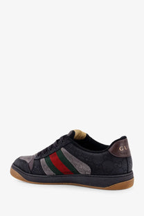 Gucci men’s GG bicolor fabric sneaker in black with red and green striped band, textured upper and brown rubber sole
