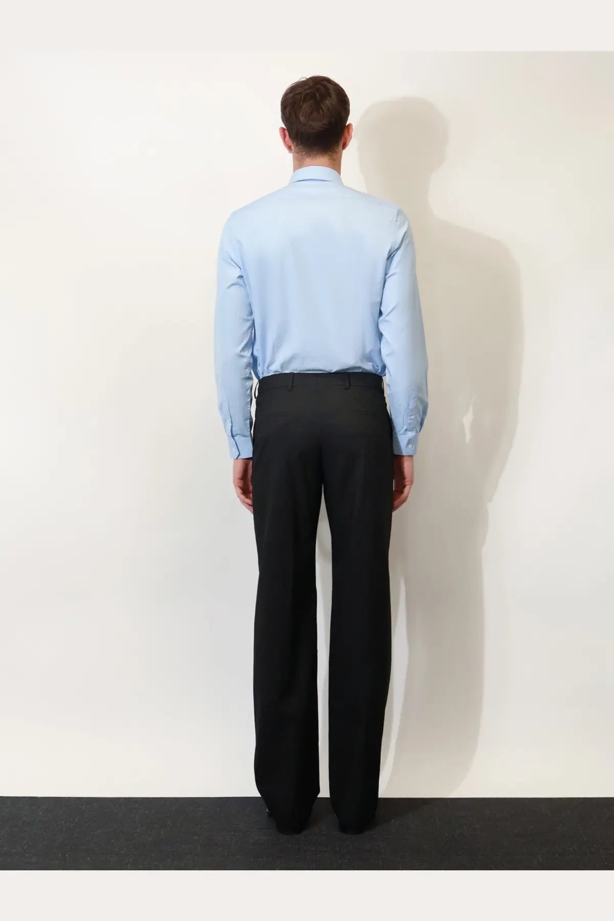 A man wearing a gucci men’s gg cotton shirt in serenity light blue with black formal trousers