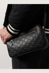 Black gucci men’s gg emblem embossed leather crossbody bag with silver hardware and red blue zipper pull
