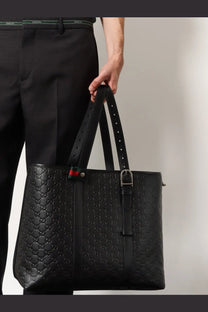 Black Gucci men’s GG emblem leather shopping bag featuring signature interlocking G pattern and red green webbing accent