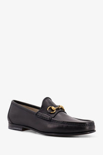 Gucci men’s horsebit leather loafer in black featuring a gold-tone horsebit buckle on the front