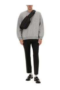 Black Gucci crossbody bag with sleek minimalist design and subtle red accent on the strap paired with grey men’s jersey sweatshirt
