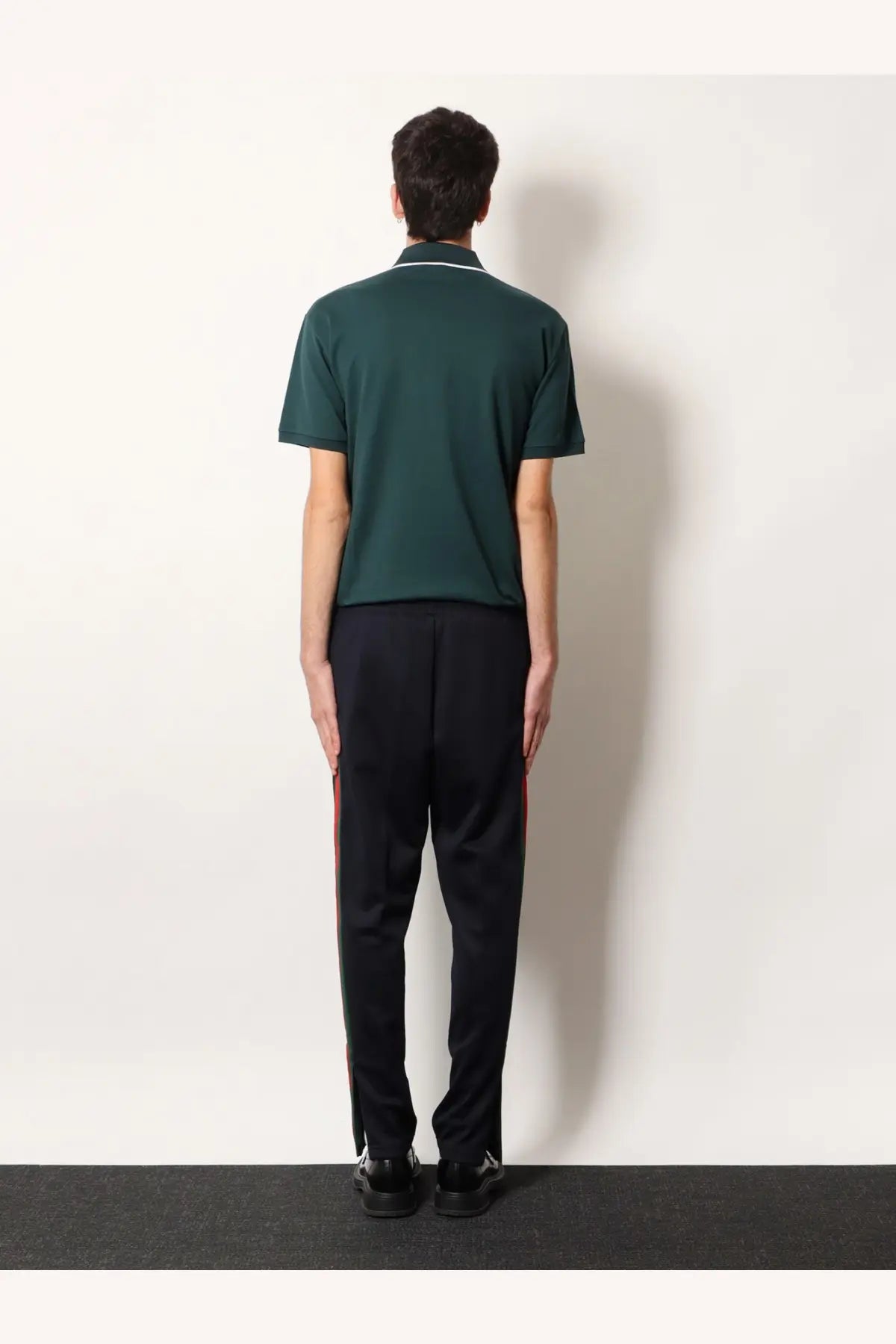 Dark green short-sleeved polo shirt with white trim on collar and cuffs paired with gucci men’s blue jersey trousers