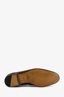 Back view of gucci men’s jordaan black leather dress loafer with tan rubber sole and stitched branding on the heel