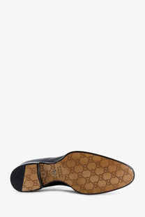 Black gucci men’s leather dress shoe with tan sole featuring the iconic gg monogram pattern for formal wear