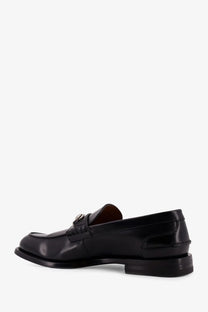 Gucci men’s black leather loafer with polished finish and decorative metal buckle on the vamp