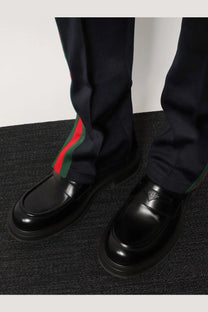 Black leather Gucci men’s loafers with glossy finish and signature red and green striped web detail on the side