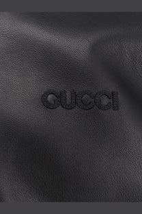 Black gucci leather bag with embossed logo complementing gucci men’s leather and wool jacket black