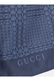 Dark blue Gucci silk scarf with repeating interlocking G logo pattern in lighter blue paired with men’s nylon swim trunks