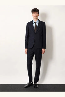 A man wearing gucci men’s grey pinstripe wool trousers paired with a dark navy pinstripe suit and light blue shirt