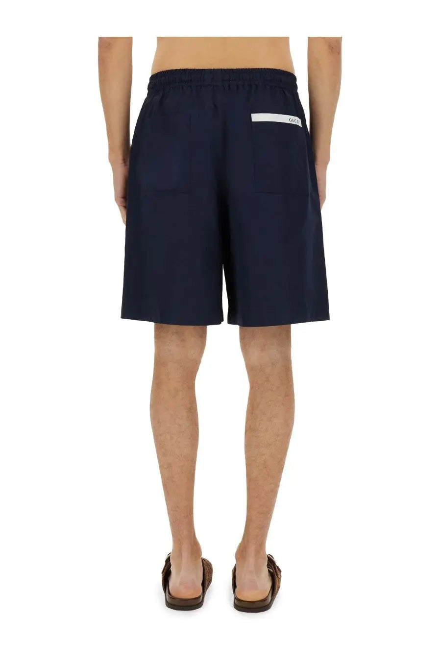 Back view of navy blue cotton gucci men’s poplin shorts with white label on the waistband