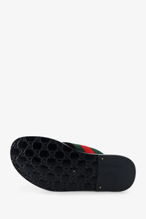 Black gucci men’s riviera leather slide sandal with glossy rubber sole embossed interlocking g logo and red green striped fabric upper