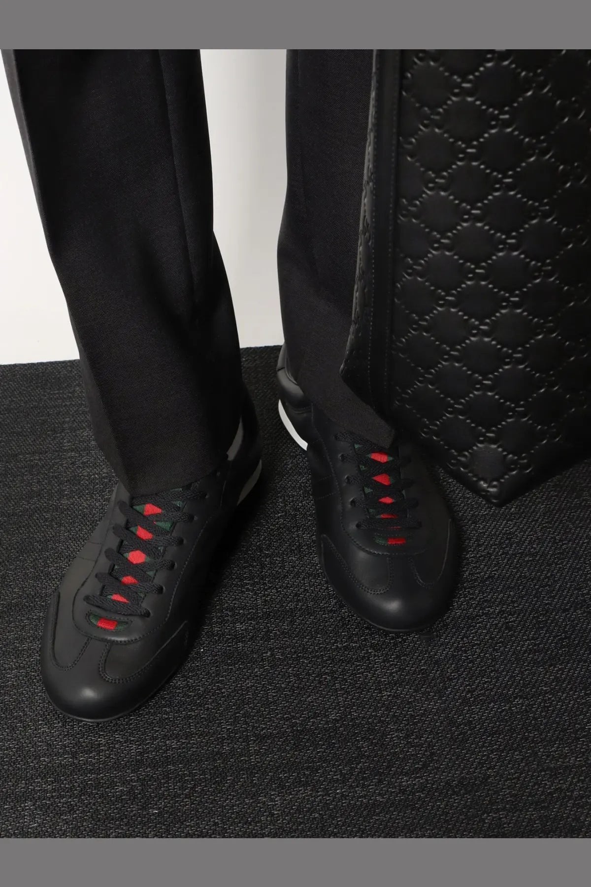 Black leather Gucci men’s sneakers with red laces and a white side stripe for stylish casual wear