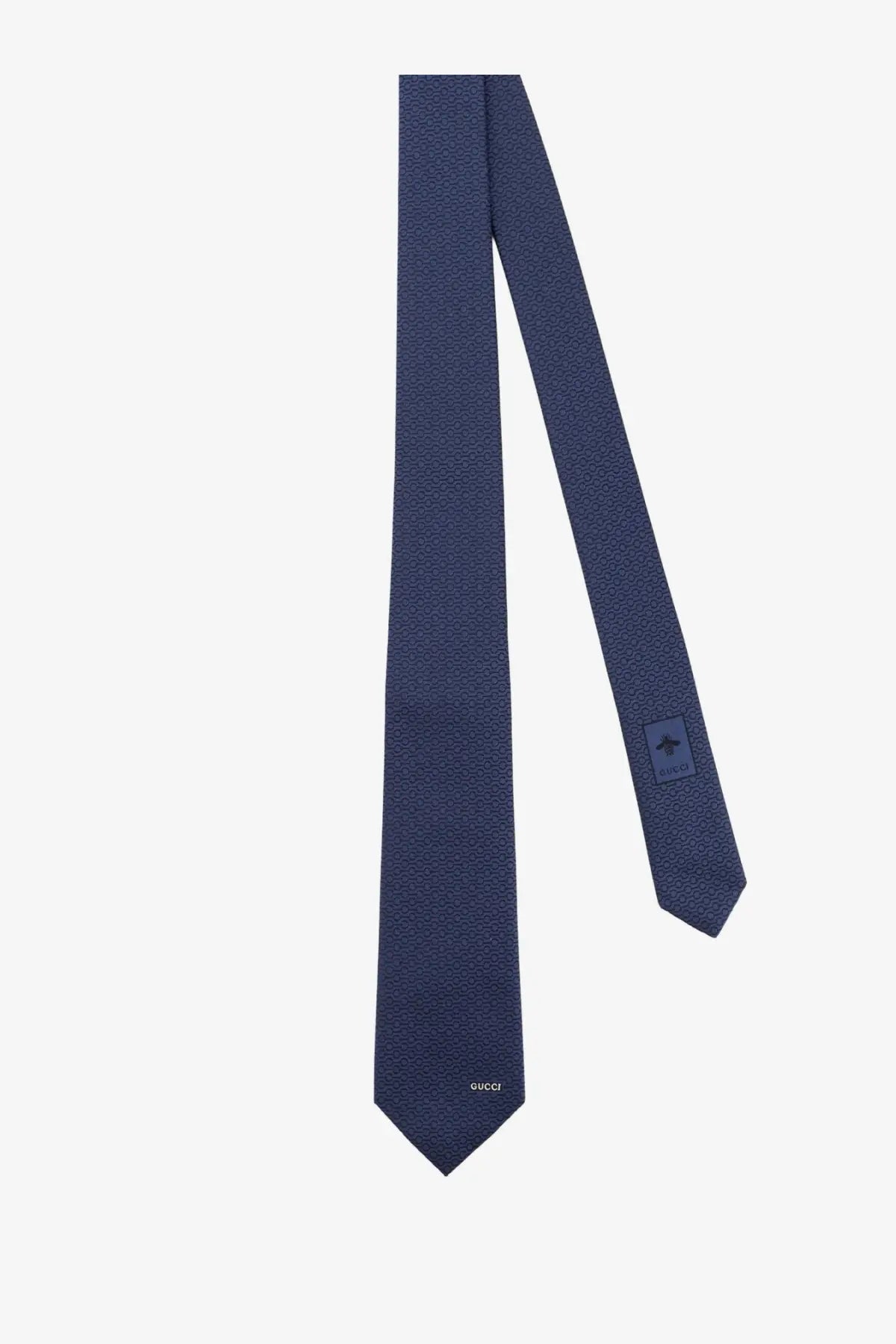 A navy blue gucci men’s silk tie with a subtle textured pattern and small woven label at the tip