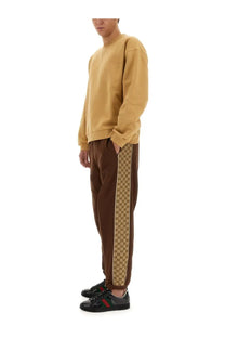 Brown Gucci men’s sweatpants with beige and brown interlocking G logo stripe down the side in cotton blend