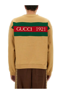 Back of gucci men’s beige sweatshirt with bold green and red striped band featuring gucci 1921 in white lettering
