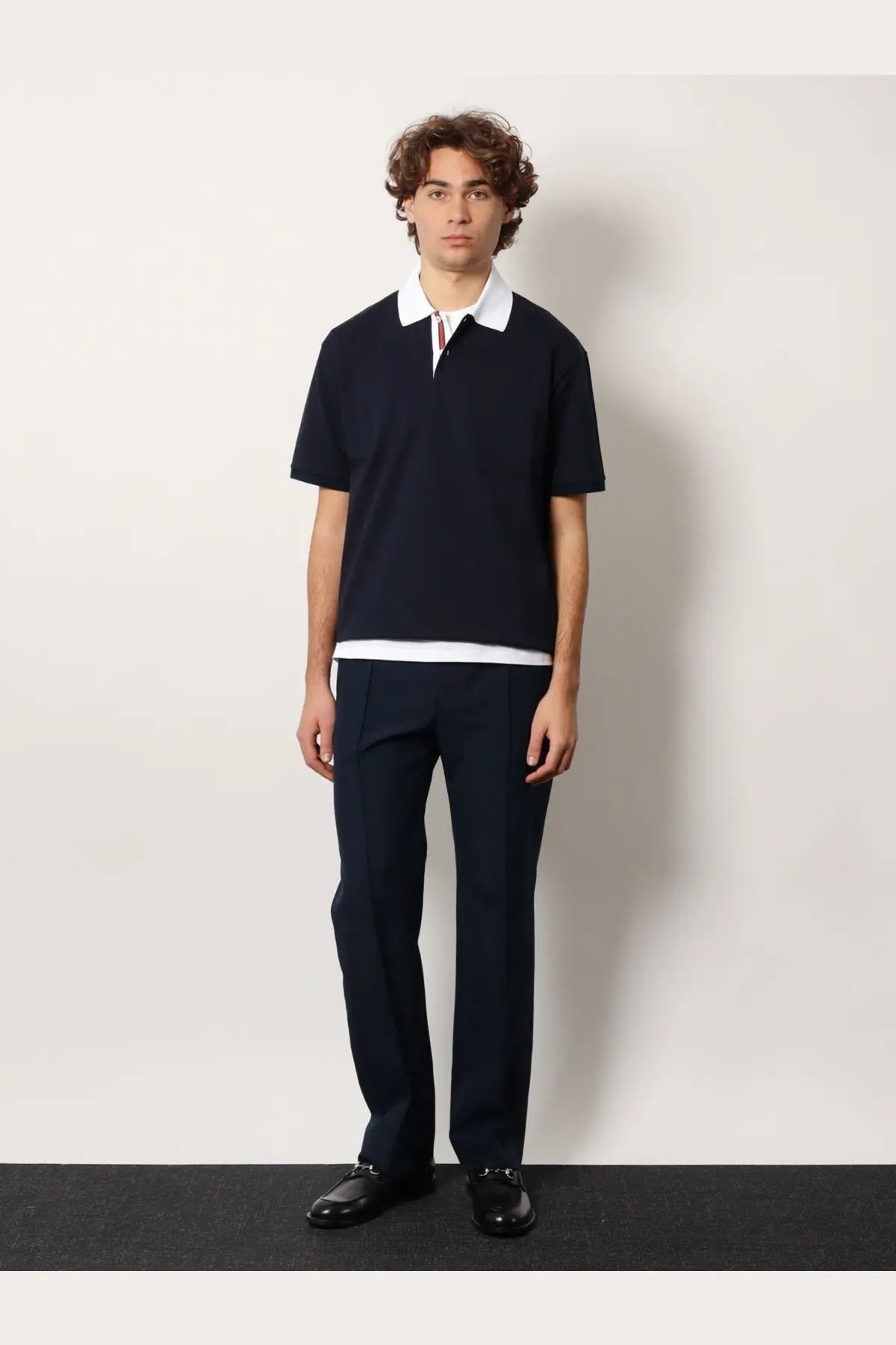 Navy blue short-sleeved polo shirt with white collar and hem featuring subtle striped placket detail
