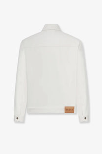 Gucci men’s white denim jacket with a brown leather patch at the bottom hem shown from the back side
