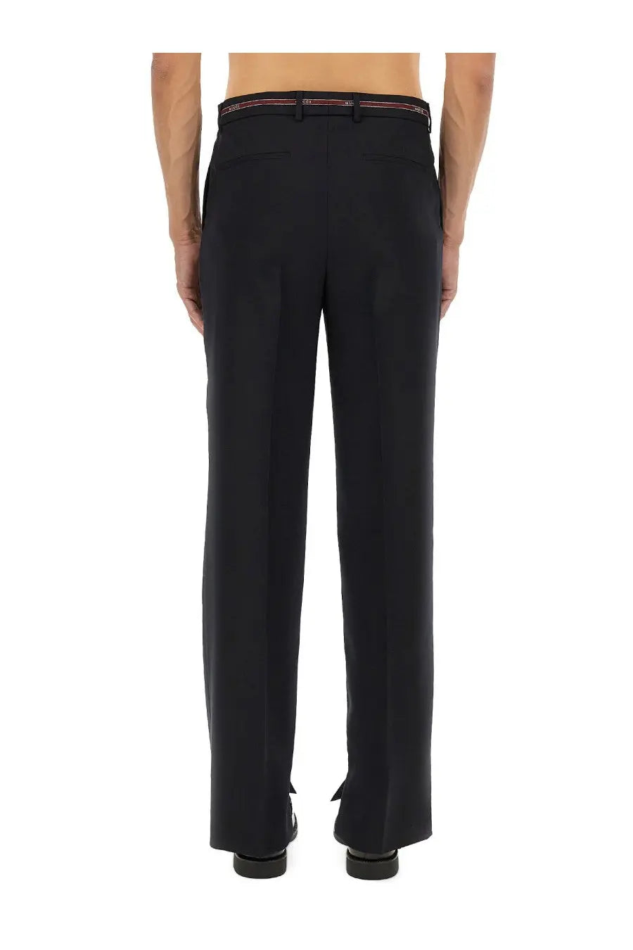 Black tailored wool trousers with slim fit and subtle pleats featuring a red and white branded belt at waistband