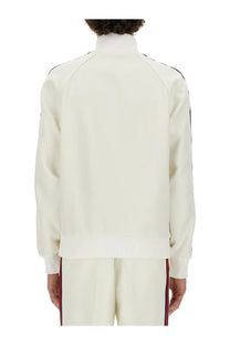 Gucci men’s cream-colored zippered track jacket with black and red striped accents on sleeves and pants