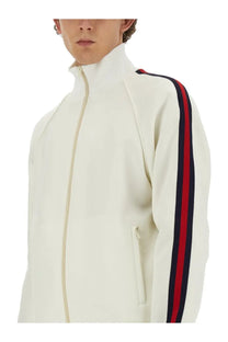 Gucci men’s cream-colored zippered track jacket with bold red and navy sleeve stripes and a high collar