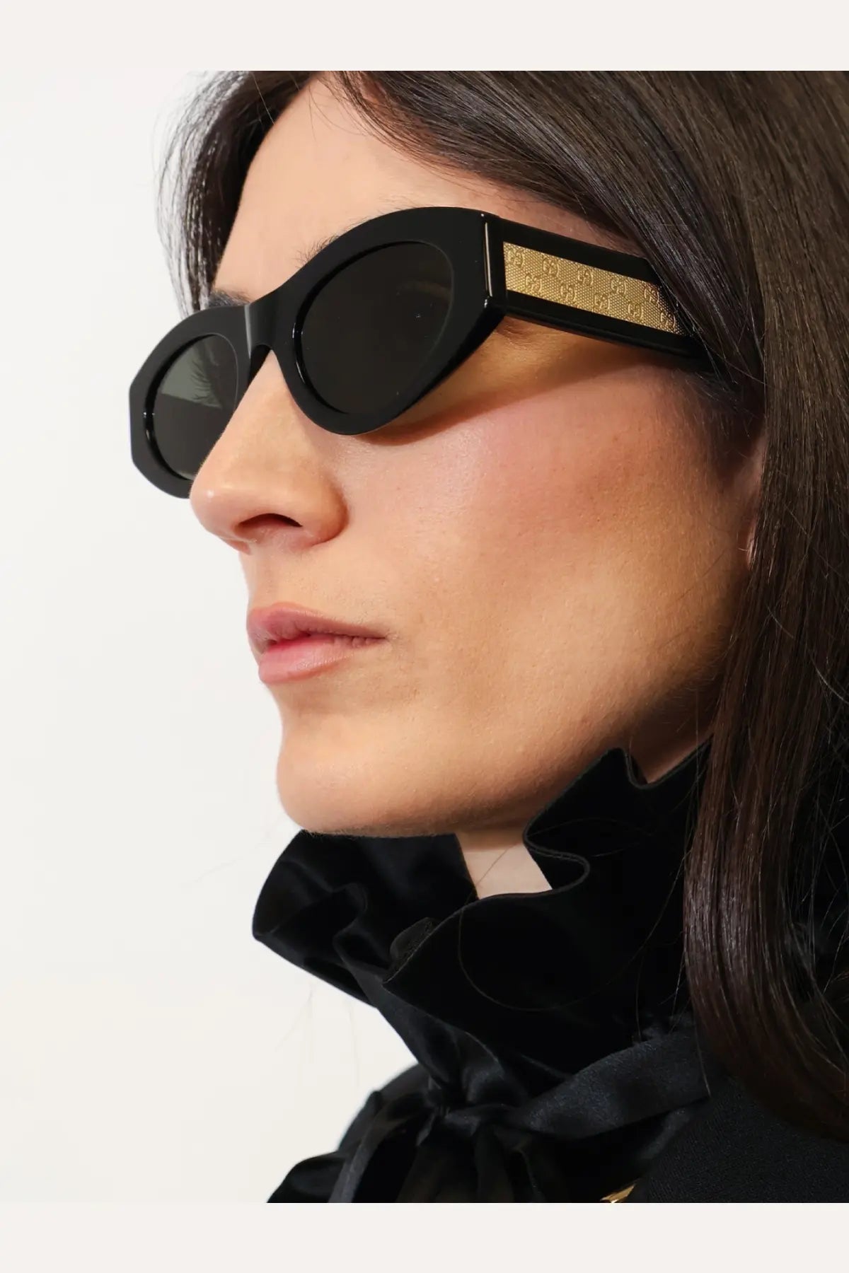 Gucci women’s black acetate oval sunglasses with a gold-tone Gucci logo band on the temple