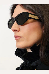 Gucci women’s black acetate oval sunglasses with a gold-tone Gucci logo band on the temple