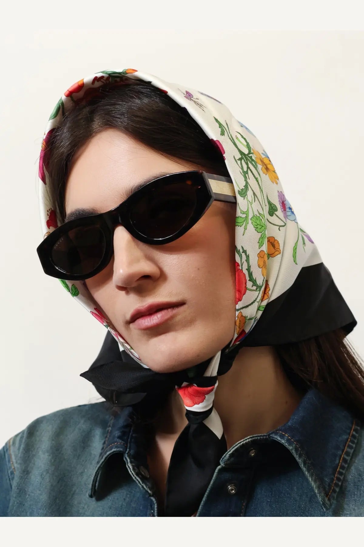 Gucci women’s brown acetate sunglasses paired with a floral-patterned cream headscarf tied around the neck