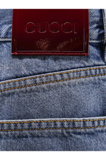 A burgundy leather gucci label stitched on the back of blue denim gucci womens cotton jeans