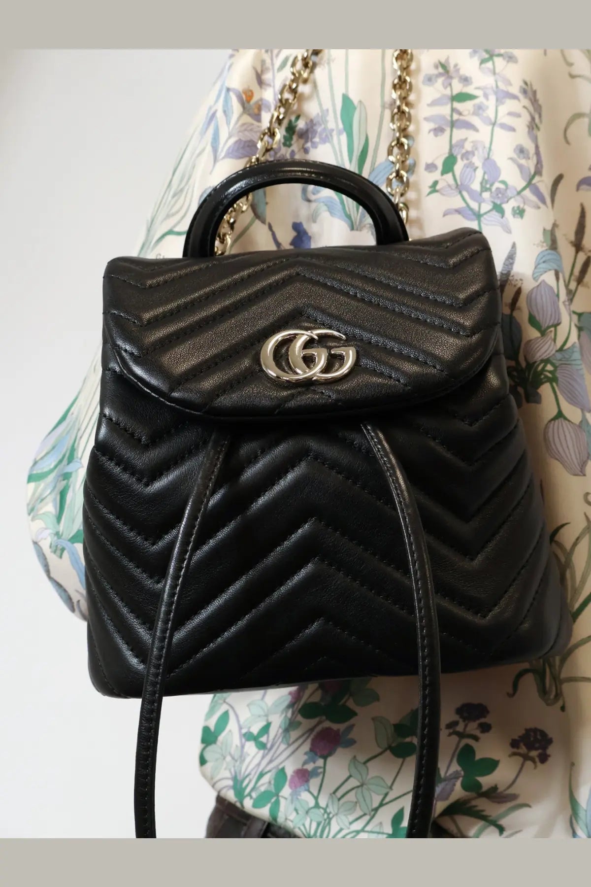 Black quilted leather Gucci women’s GG Marmont mini backpack with silver double G logo clasp and chain strap