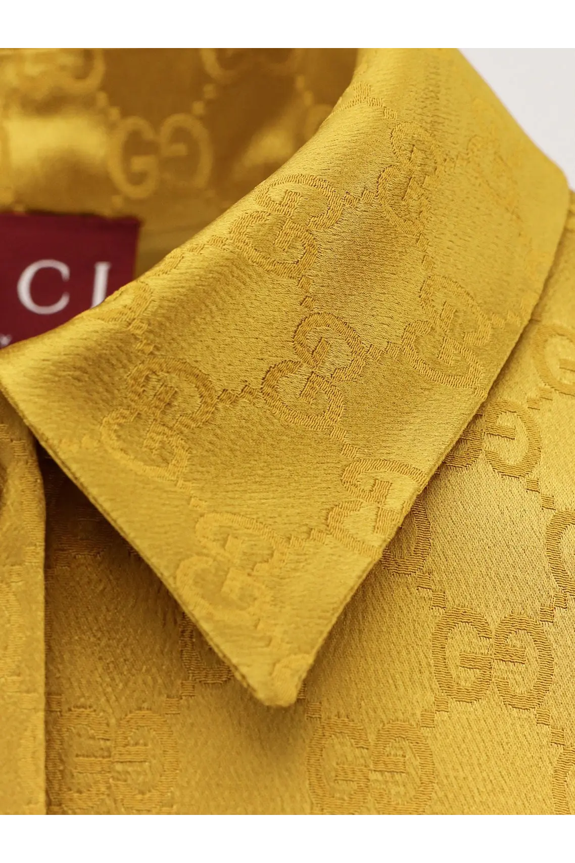Golden Gucci shirt with repeating gg monogram pattern woven into fabric from Gucci women’s GG satin chemisier dress white