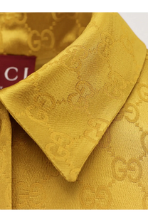 Golden Gucci shirt with repeating gg monogram pattern woven into fabric from Gucci women’s GG satin chemisier dress white