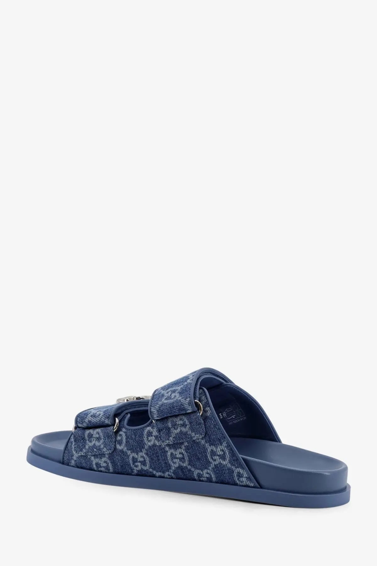 Gucci women’s laser GG denim sandals in blue featuring denim pattern, metallic buckle, and rubber sole