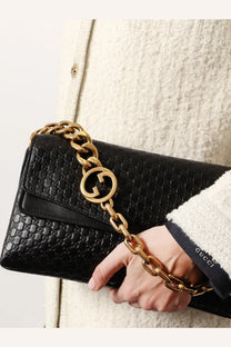Gucci women’s black leather crossbody bag with gold-tone chain strap and signature interlocking g logo