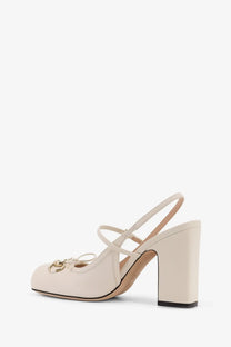 Cream-colored Gucci women’s leather écolleté suede slingback pump with gold-tone horsebit buckle and crisscross straps