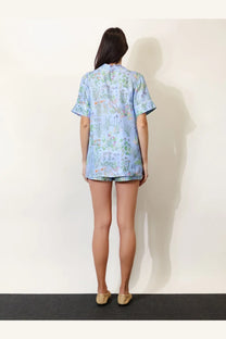 Gucci women’s printed silk shirt in white featuring light blue floral print short sleeves with ruffled cuffs and collar