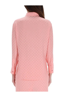 Back side of a soft pink gucci womens silk shirt featuring a subtle repeating gg logo pattern on back and sleeves