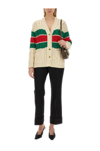 Gucci women’s black wool pants paired with a cream-colored knitted cardigan with green and red stripes and gold buttons