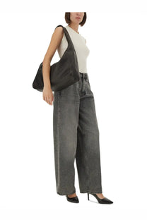 Black leather shoulder bag with slouchy minimalist design paired with haikure women’s bethany jeans grey