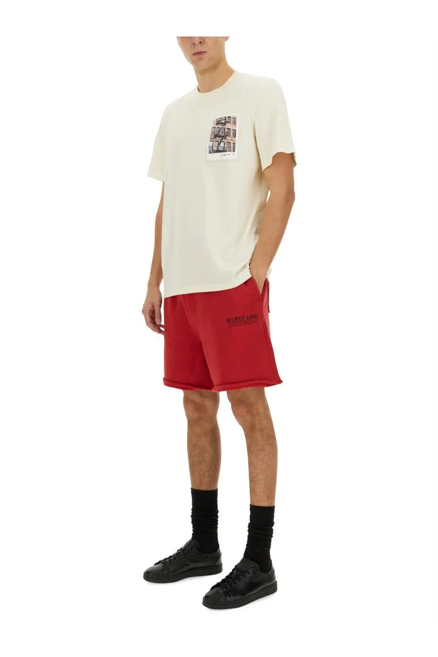 Red athletic shorts with black side text and subtle rolled hem paired with helmut lang men’s postcard building shirt white