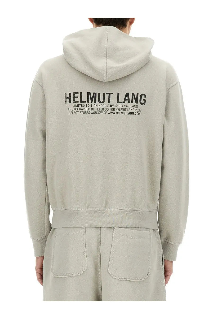 Back side of a beige helmut lang limited edition hoodie with a bold black printed logo in men’s postcard grey style