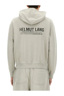Back side of a beige helmut lang limited edition hoodie with a bold black printed logo in men’s postcard grey style