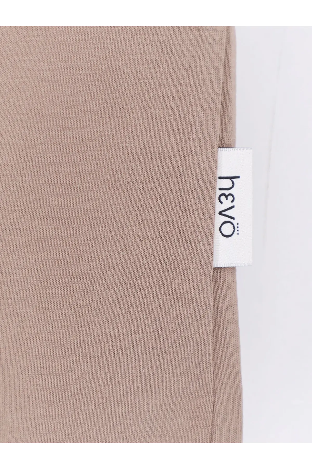 Beige ribbed knit fabric of hevò men’s mulino cotton shirt with white label featuring the hevò brand name