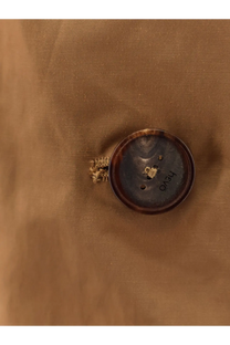 A dark brown textured circular button with two holes on the hevò women’s cala paradiso cotton blend raincoat